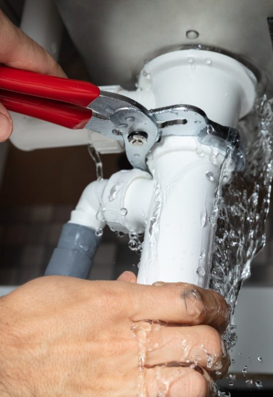 Close-up Of Male Plumber Fixing White Sink Pipe With Adjustable Wrench